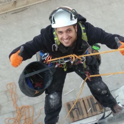 אדם עם קסדה ורתמה בעבודת גובה על חבל