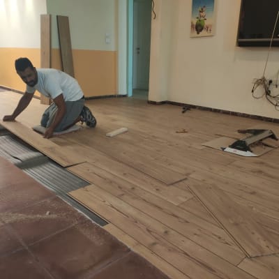 אדם מתקין פרקט עץ על רצפה בחדר