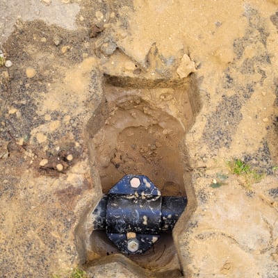 צינור מתכת עם חיבור ברגים בתוך חפירה באדמה