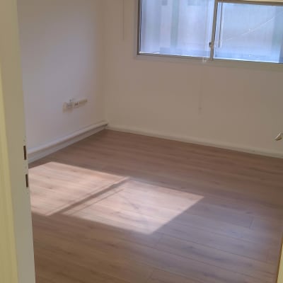 חדר ריק עם רצפת עץ נקייה וחלון עם תריסים