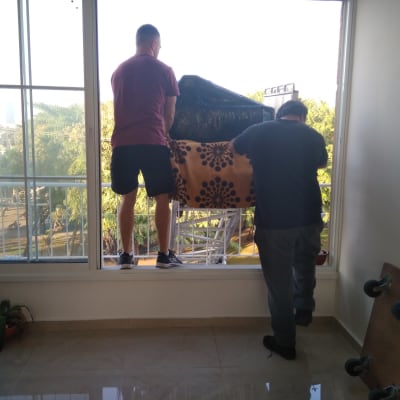 שני אנשים מעבירים רהיט דרך חלון פתוח