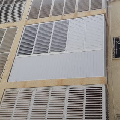 תריסי אלומיניום לבנים על קיר חיצוני של בניין