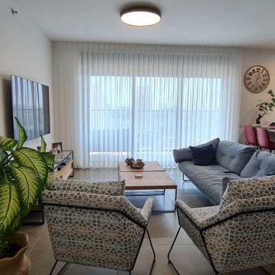 וילון לבן שקוף תלוי על חלון גדול בסלון