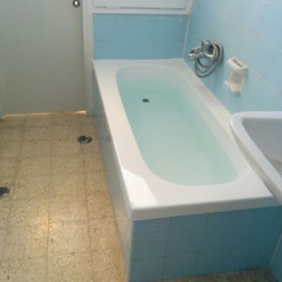 אמבטיה עם חיפוי אריחים כחולים וברז מתכת