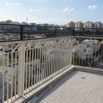 מעקה מתכת לבן עם עיטורים גיאומטריים במרפסת