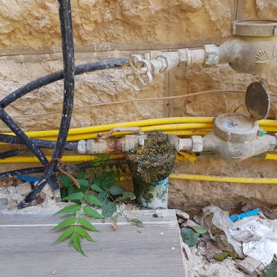 צינורות מים וברזים על קיר אבן