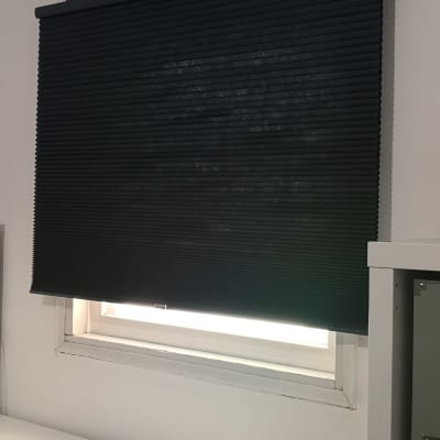 תריס גלילה שחור מותקן על חלון מתחת למזגן