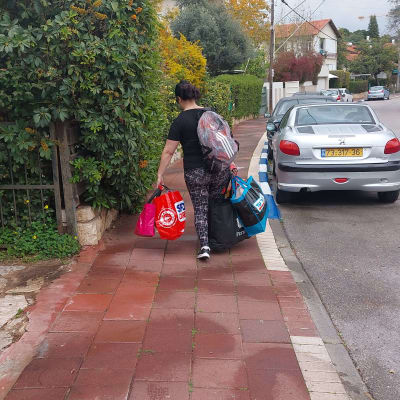 אישה נושאת שקיות קניות צבעוניות על מדרכה