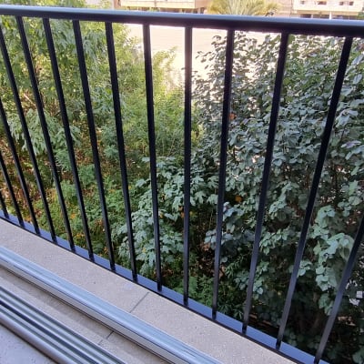 מעקה מתכת שחור עם מוטות אנכיים במרפסת