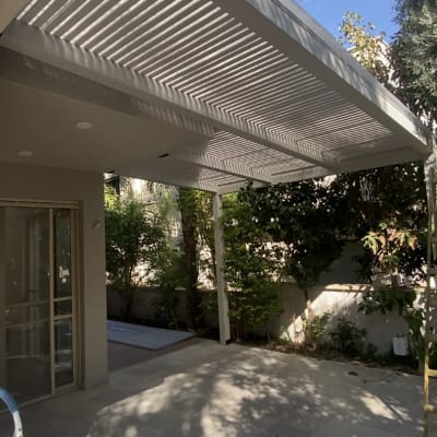 פרגולה לבנה עם צללים על הרצפה בגינה