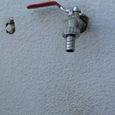 ברז מתכת עם ידית אדומה על קיר