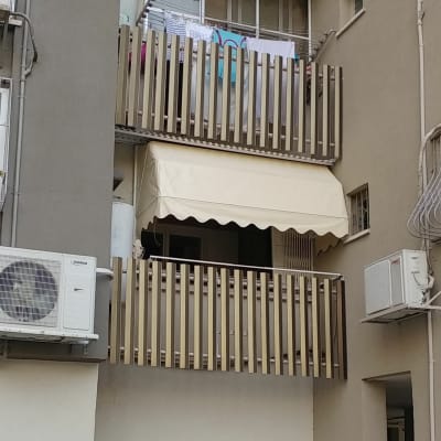 סוכך בד בהיר על מרפסת עם מעקה עץ