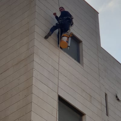 אדם על חבל עם דלי ליד קיר בניין