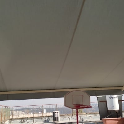 סוכך בד מתוח מעל מרפסת עם צמחייה מסביב