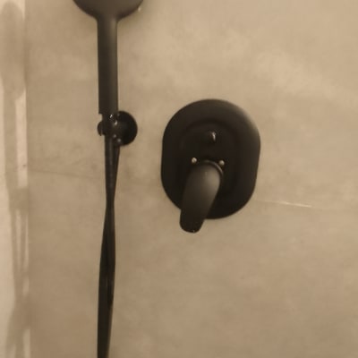 ראש מקלחת וברז שחור על קיר אמבטיה