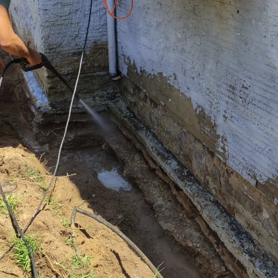 אדם משתמש במכונת שטיפה בלחץ על קיר חיצוני