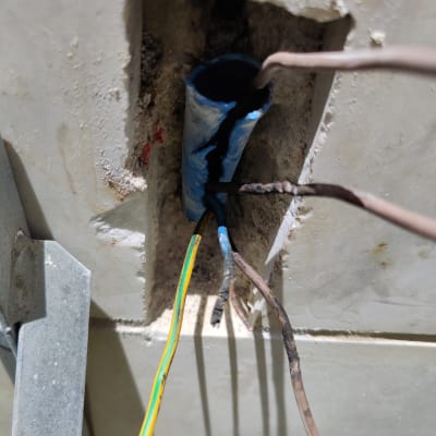 חוטי חשמל יוצאים מצינור כחול בקיר