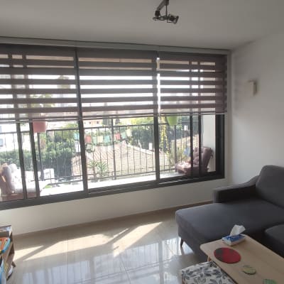 וילון גלילה חום על חלון גדול בסלון מואר