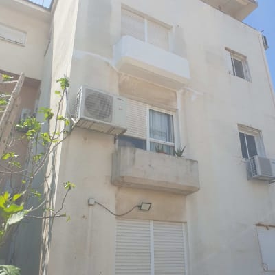 קיר חיצוני עם סימני תיקון ושלט שיפוצים