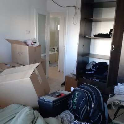 חדר עם קרטונים, ארון פתוח ותיק גב.