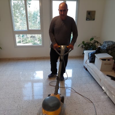 אדם מנקה רצפה עם מכונת פוליש בחדר מואר