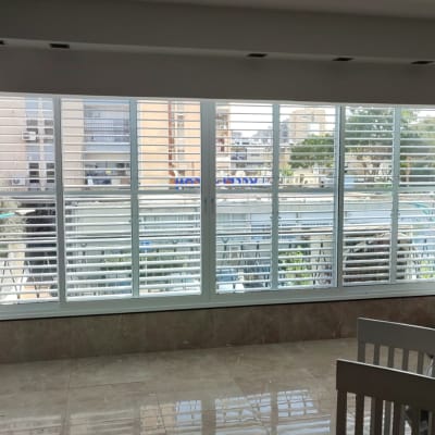 תריסי אלומיניום לבנים בחלון גדול