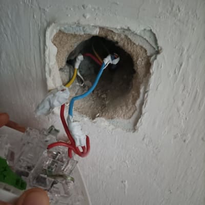 חוטי חשמל צבעוניים יוצאים מקיר עם שקע פתוח