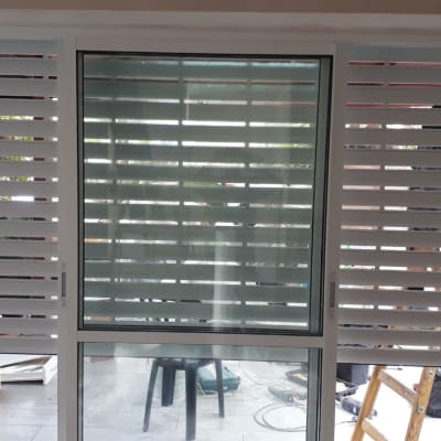 תריסים לבנים מותקנים על חלון זכוכית עם כלי עבודה