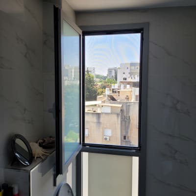 חלון אלומיניום פתוח עם נוף עירוני ברקע