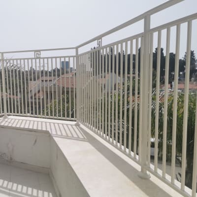 מעקה מתכת לבן על מרפסת עם רצפת אריחים