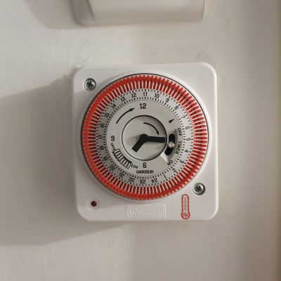 טיימר חשמלי עם חוגה אדומה על קיר לבן