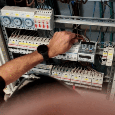 חשמלאי עובד על לוח חשמל עם מפסקים