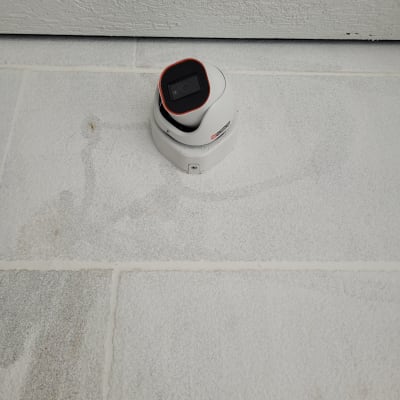 מצלמת אבטחה לבנה מותקנת על קיר לבן