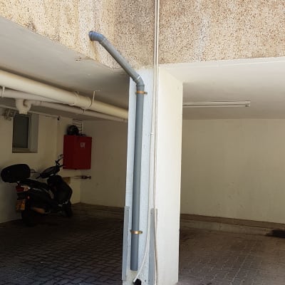 צינור אפור מחובר לקיר עם נזילת מים