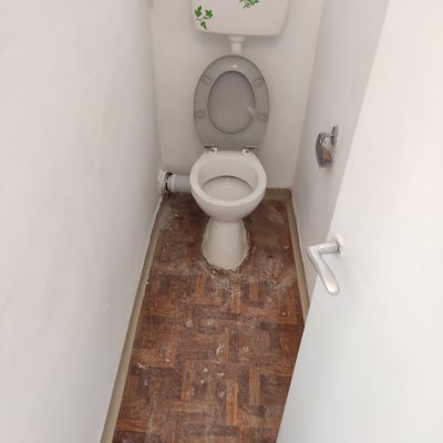 אסלה עם מכסה פתוח בחדר שירותים קטן