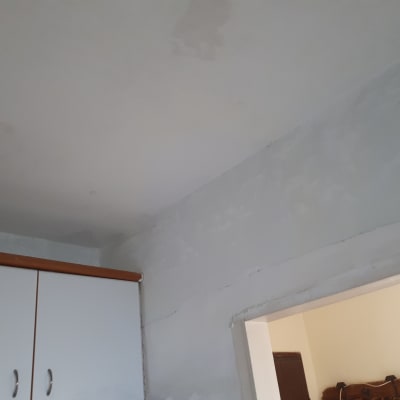 קיר ותקרה צבועים בלבן עם סימני תיקון