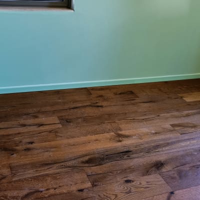 רצפת פרקט עץ כהה בחדר עם קיר ירוק