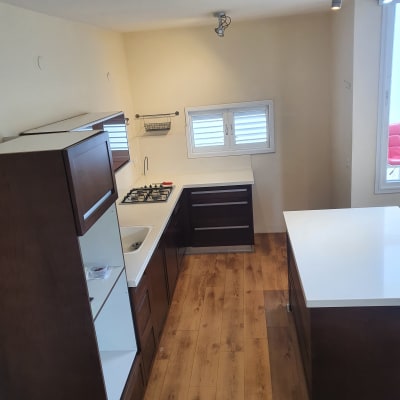 מטבח נקי עם משטחי עבודה לבנים וכיור