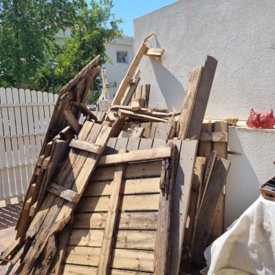 ערימת קרשים ישנים ליד קיר לבן