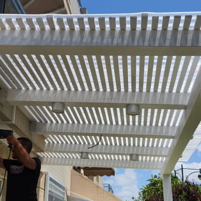 שני אנשים מתקינים פרגולה לבנה עם מקדחה