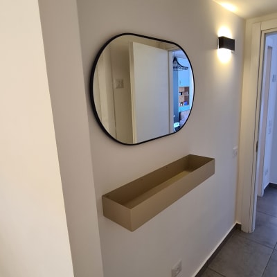 מראה עגולה תלויה על קיר עם מדף מתחת