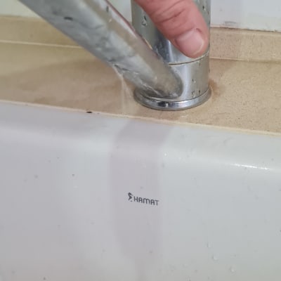 יד מחזיקה ברז נירוסטה עם מים זורמים