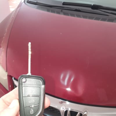 מפתח רכב מול מכסה מנוע של רכב אדום