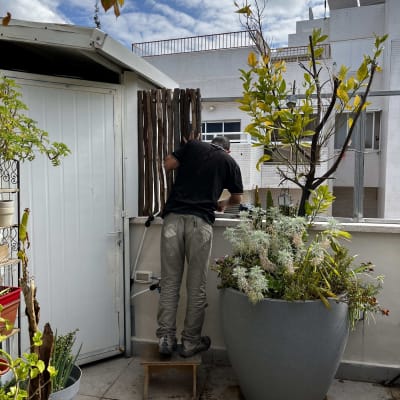 אדם עובד בגינה ליד עציץ גדול עם צמחים