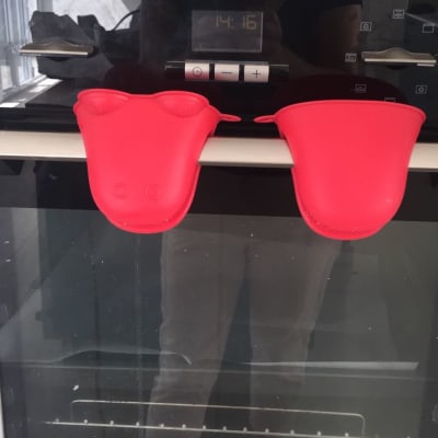 תנור אפייה עם כפפות סיליקון אדומות על הידית