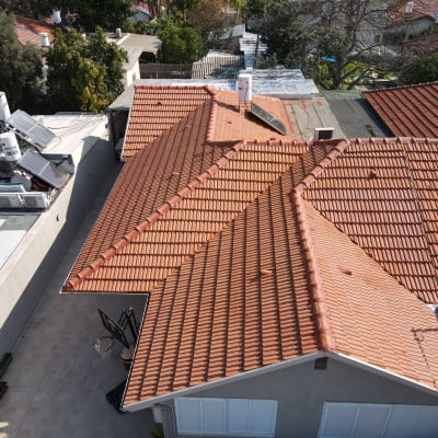 גג רעפים אדום עם דודי שמש וקולטים