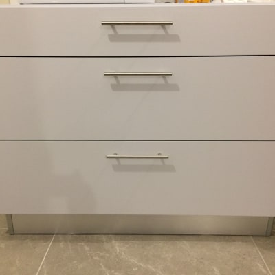 ארון מטבח לבן עם שלוש מגירות וידיות מתכת