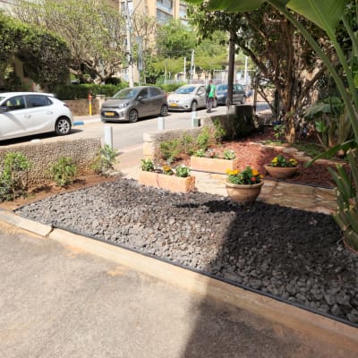 אדניות עם פרחים, אבנים שחורות, צמחים ירוקים