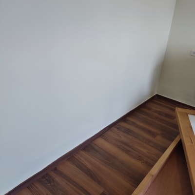 קיר צבוע בלבן עם רצפת עץ כהה