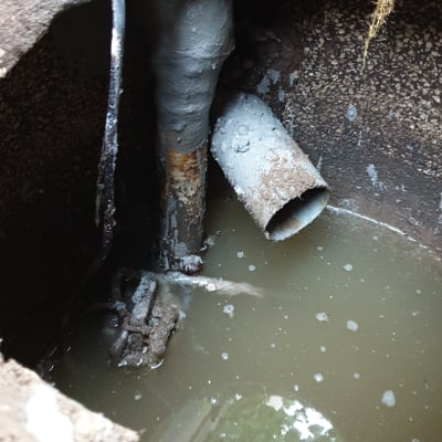 צינור מתכת חלוד בתוך בור עם מים